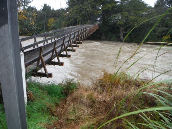The river high and dirty under the Koura Street swing bridge.